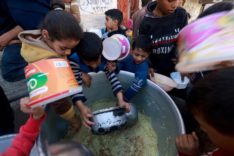 Palestinian children collect food at a donation point provided by a charity group in the southern Gaza Strip city of Rafah. AFP