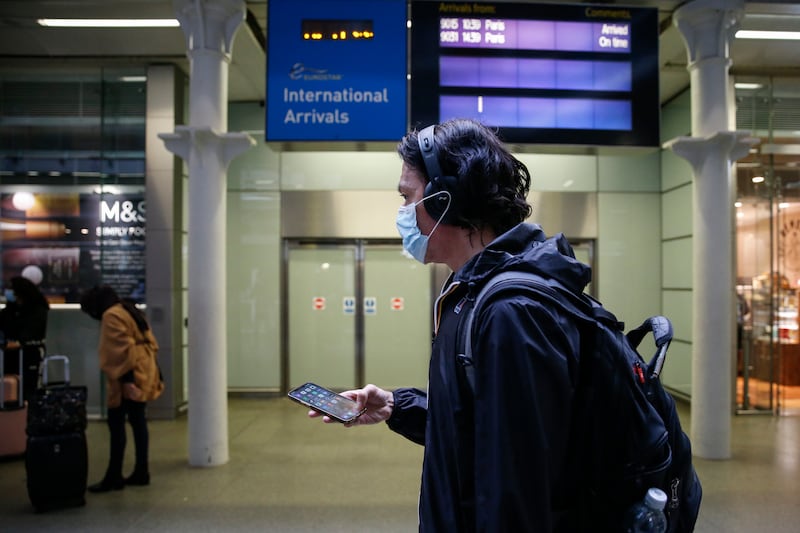 A man wearing a face mask walks past the arrivals gate at St Pancras International station in London. Getty Images