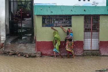 Residents walk along a house on a flooded street heading to a shelter ahead of the expected landfall of cyclone Amphan, in Dacope of Khulna district on May 20, 2020. Several million people were taking shelter and praying for the best on Wednesday as the Bay of Bengal's fiercest cyclone in decades roared towards Bangladesh and eastern India, with forecasts of a potentially devastating and deadly storm surge. Authorities have scrambled to evacuate low lying areas in the path of Amphan, which is only the second "super cyclone" to form in the northeastern Indian Ocean since records began. / AFP / Munir uz Zaman