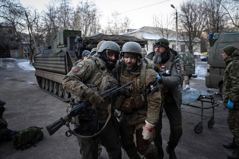 A Ukrainian serviceman carries his injured comrade from the battlefield to a hospital in the Donetsk region. AP