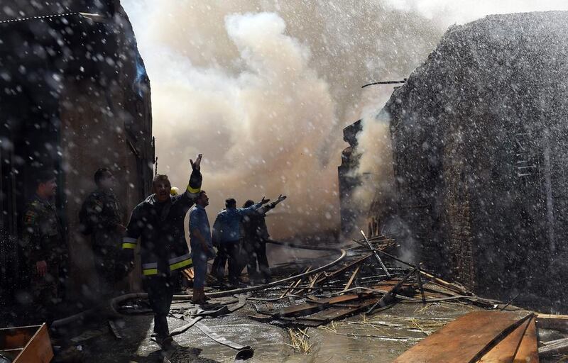 Afghan firefighters try to extinguish a fire at a wood market at Quwai Markaz in Kabul. AFP