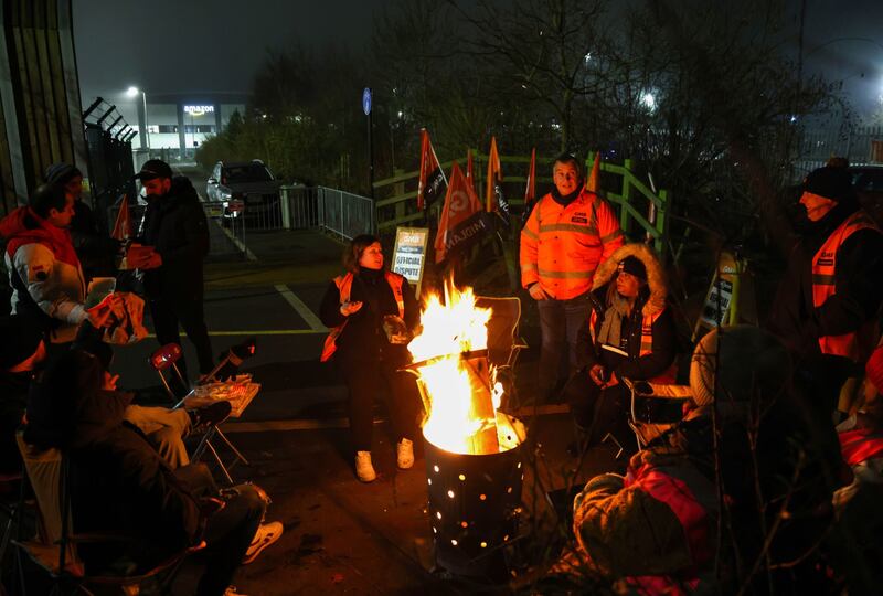 Striking workers gather around a fire pit. Bloomberg