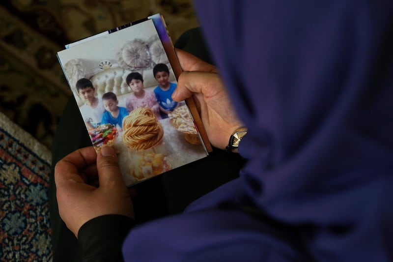 In this Aug. 20, 2018, photo, Meripet, 29, holds on to a photograph of her children in Istanbul, Turkey. Meripet came to Turkey in February 2017 to visit her sick father, leaving four children behind, her oldest son Abdurahman, 8, daughter Adile, 6, son Muhemmed, 4, and son Abdulla, 3. While in Turkey, she heard Uighur passports were being seized and that people who had gone abroad were being taken to reeducation â€“ so she stayed in Turkey, giving birth to Abduweli. She hasn't seen her other four children since, and heard they were taken to a live-in kindergarten in Hotan, China. (AP Photo/Dake Kang)