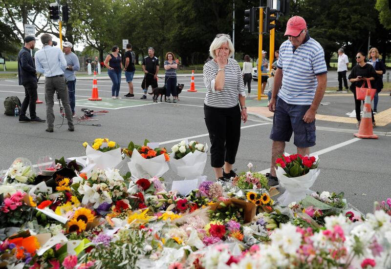 People react near flowers placed at a memorial as a tribute to victims of the mosque attacks, near a police line outside Masjid Al Noor in Christchurch, New Zealand. Reuters