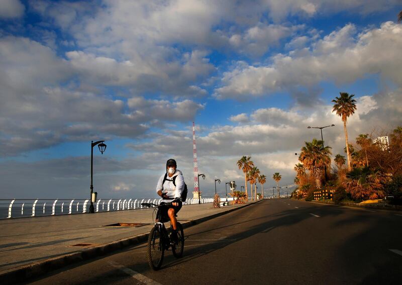 A man wears a mask as he rides a bicycle on Beirut's deserted corniche. AP Photo