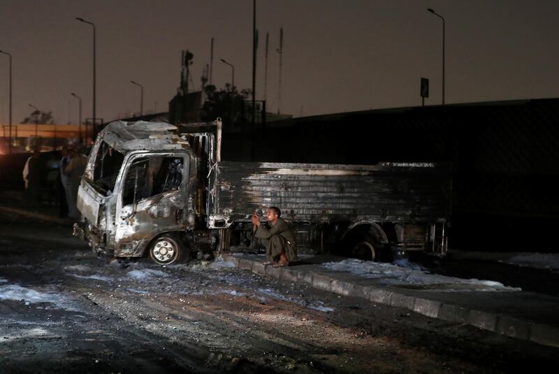 A man sits next to a burned truck following a fire that broke out in Egypt's Shuqair-Mostorod crude oil pipeline, at the beginning of Cairo-Ismailia road, Egypt. REUTERS