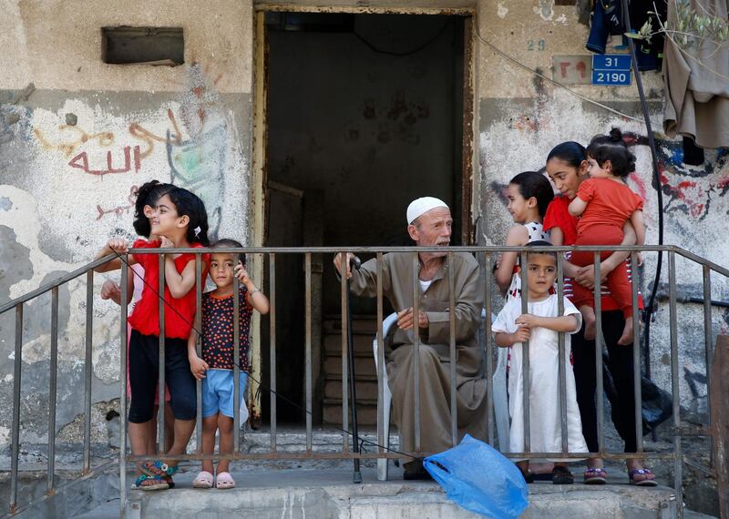 A Palestinian sits outside a home surrounded by children in Gaza City. EPA