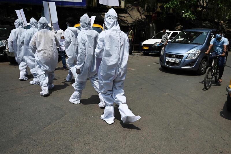 Protesters wearing hazmat suits demonstrate near the Election Commission office in Kolkata on April 7, 2021. They demand that the ongoing state legislative election and campaign rallies be put on hold because of the rise in coronavirus cases. AFP