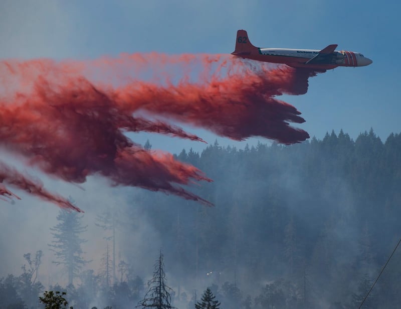 An air tanker drops retardant on a fire burning on the east side of Mount Pisgah near Eugene, Oregon. The Register-Guard via AP