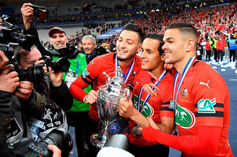 Rennes defenders Ramy Bensebaini and Mehdi Zeffane, and forward Hatem Ben Arfa celebrate with the trophy. Damien Meyer / AFP