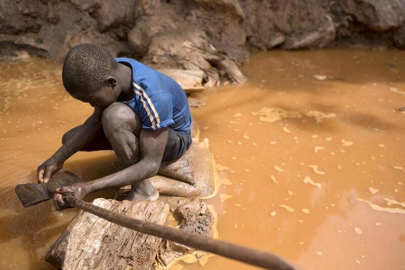 A boy cleans a shovel before panning for gold near the open pit Ndassima at the gold mine near Djoubissi. Siegfried Modola / Reuters