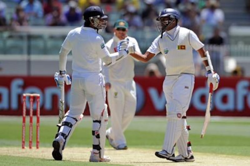 Sri Lanka batsman Kumar Sangakkara is congratulated by teammate Thila Samaraweera after reaching the 10,000 Test runs landmark against Australia.