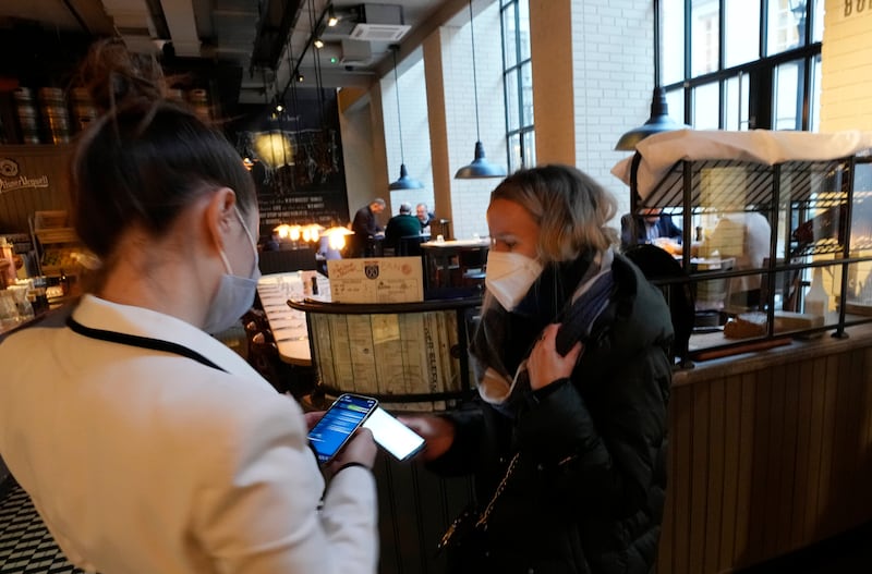A restaurant worker in Warsaw checks a customer's proof of vaccination. From March, Poland's health workers, teachers, police and other uniformed service workers will need to be vaccinated against Covid-19. AP