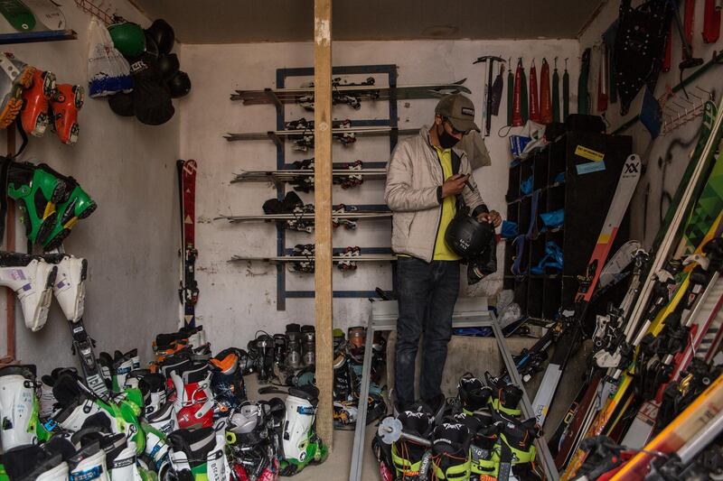 Said Ali Shah Farhang, 29, sorts through skiing equipment in his office, wearing a mask to protect from coronavirus risks. 