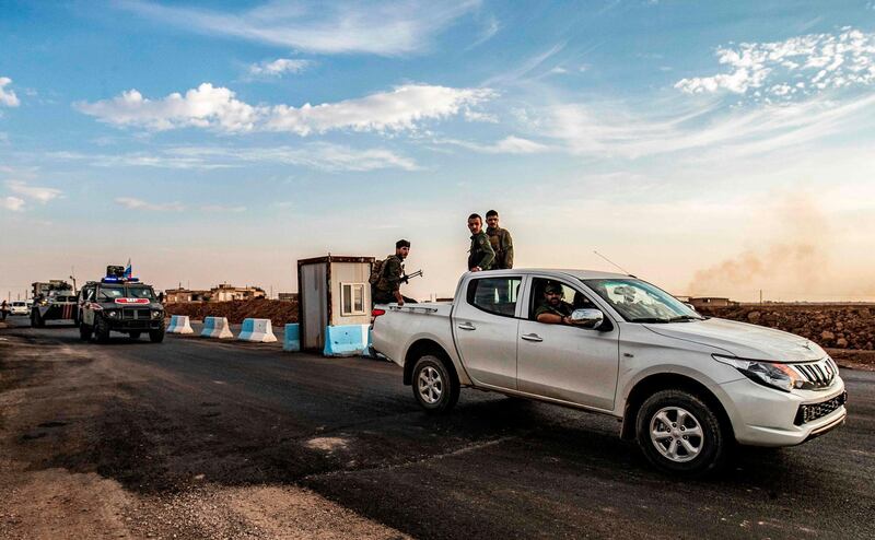 Members of the Syrian Kurdish Asayish internal security forces ride in the back of a pickup truck during a joint patrol with Russian military police vehicles in Amuda. AFP