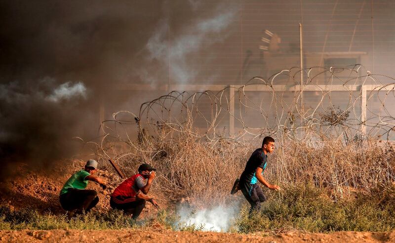 Palestinian protesters hide from tear gas during a demonstration near the border with Israel, east of Gaza City, on August 31, 2018. AFP