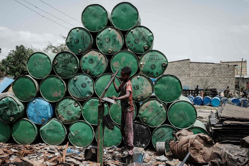 A boy makes a part for a coffee pot, next to a stack of oil drums set for recycling, in Mekele, capital of Tigray region, Ethiopia. AFP