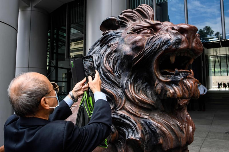 A man takes a photo of a lion statue outside HSBC bank headquarters building in Hong Kong. AFP