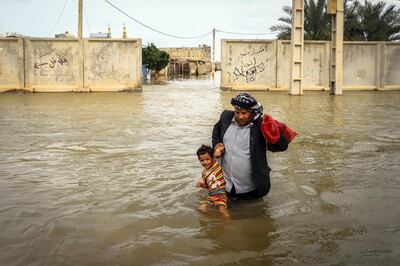 epa07480225 An Iranian man carries his son in a flooded way in a village around the city of Ahvaz, Khuzestan province, Iran, 31 March 2019 (issued 02 April 2019).  At least 45 people have died in the past two weeks after heavy rains, with flooding affecting at least 23 of the country's 31 provinces.  EPA/SAEED SOROUSH