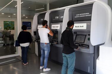 Customers use automated teller machines at a Bank Audi bank branch. Banks have been closed in the country for almost two weeks and the central bank governor says no capital controls will be imposed. Bloomberg