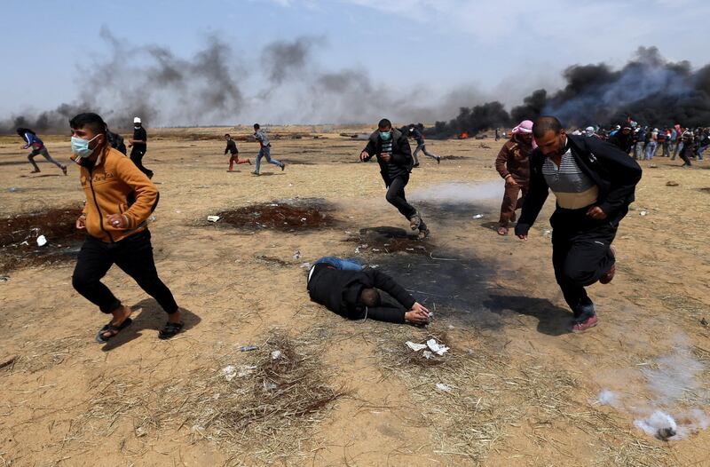 A wounded Palestinian falls on the ground during clashes with Israeli troops at a protest where Palestinians demand the right to return to their homeland, at the Israel-Gaza border in the southern Gaza Strip, April 27, 2018. REUTERS/Ibraheem Abu Mustafa     TPX IMAGES OF THE DAY