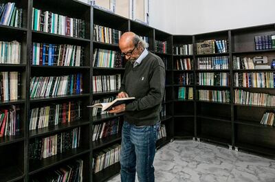 Ziad al-Hamad, director of the first cultural centre to open since the Islamic State (IS) group's rule ended in the eastern Syrian city of Raqa. holds a book as he stands in its library on May 1, 2019. More than a year after Islamic State group jihadists fled, Syrian boys and girls are back on stage bobbing to the rhythm of drums in the northern city of Raqa. Sunlight floods into a brand new libraryat the cultural centre where books line shelves along a wall that still smells of wet paint. / AFP / Delil souleiman
