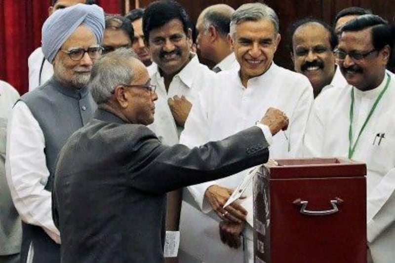 India's ruling alliance candidate Pranab Mukherjee casts his vote in India's presidential election as Prime Minister Manmohan Singh, left, along with other politicians, look on in New Delhi, yesterday.