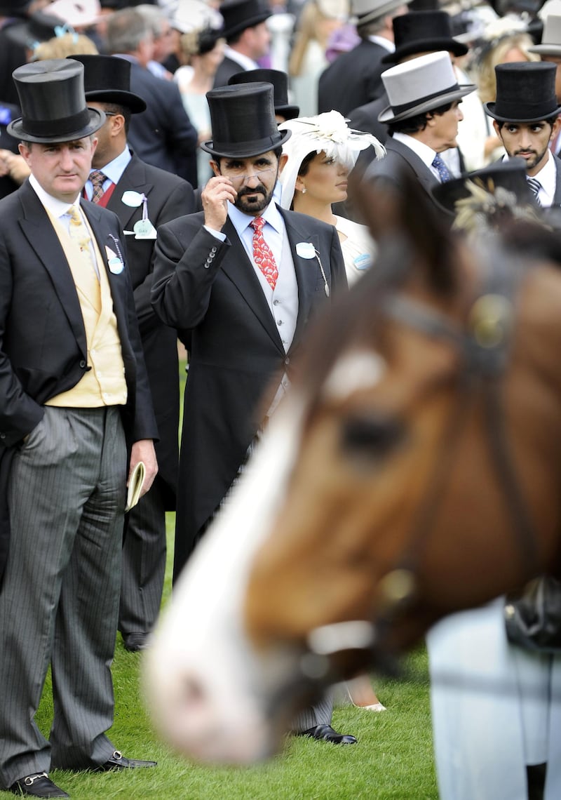 Sheikh Mohammed bin Rashid Al Maktoum, Ruler of Dubai,(C)  tips his glasses to view a race horse in the parade ring during the first day of Royal Ascot, in Berkshire, west of London, on June 16, 2009. The five-day meeting is one of the highlights of the horse racing calendar. Horse racing has been held at the famous Berkshire course since 1711 and tradition is a hallmark of the meeting. Top hats and tails remain compulsory in parts of the course while a daily procession of horse-drawn carriages brings the Queen to the course. AFP PHOTO/Adrian Dennis (Photo by ADRIAN DENNIS / AFP)