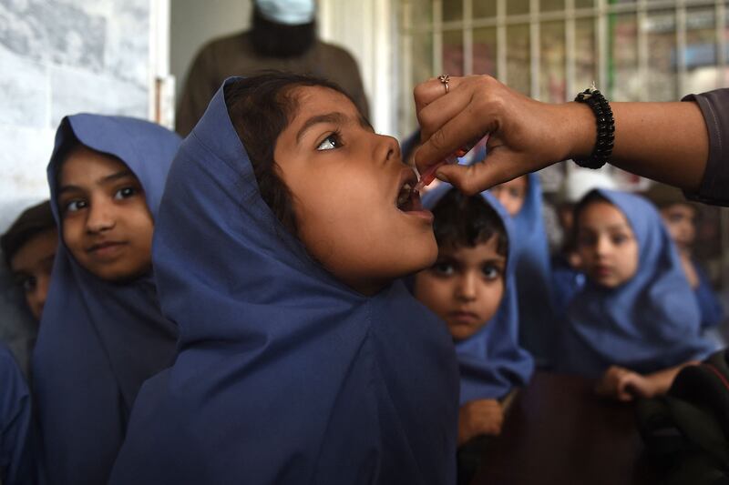 A health worker administers polio vaccine drops to a young girl during an inoculation campaign in Karachi, Pakistan. AFP