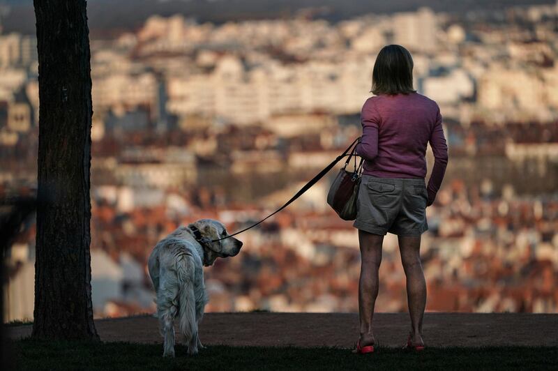 A woman and her dog stand on a hill above Lyon, central France, on March 20, 2020. AP Photo