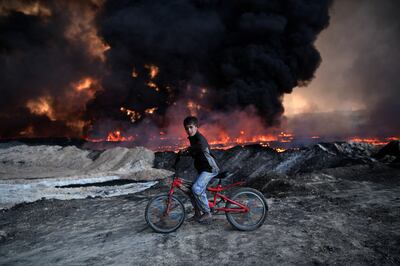 A boy pauses on his bike as he passes an oil field that was set on fire by retreating ISIS fighters in Qayyarah, Iraq in 2016. ISIS once targeted drought-affected Sunni-majority areas of the country, exploiting grievances about water scarcity and loss of agricultural livelihoods. Getty