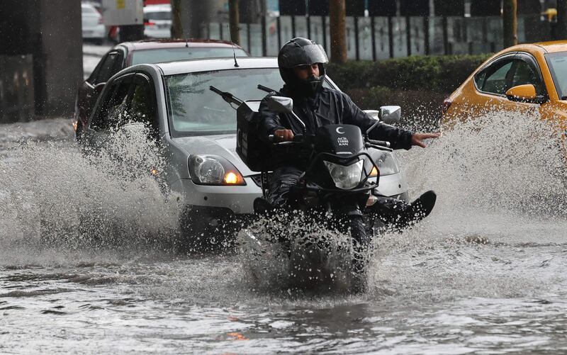 A man on a motorcycle drives through a street flooded by heavy rain, in Ankara. AFP