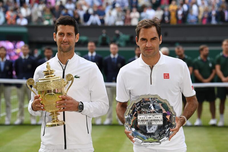 (FILES) In this file photo taken on July 14, 2019 Serbia's Novak Djokovic (L) poses with the winner's trophy and Switzerland's Roger Federer (R) holds the runners up plate during the presentation after the men's singles final on day thirteen of the 2019 Wimbledon Championships at The All England Lawn Tennis Club in Wimbledon, southwest London. RESTRICTED TO EDITORIAL USE
 / AFP / Ben STANSALL / RESTRICTED TO EDITORIAL USE
