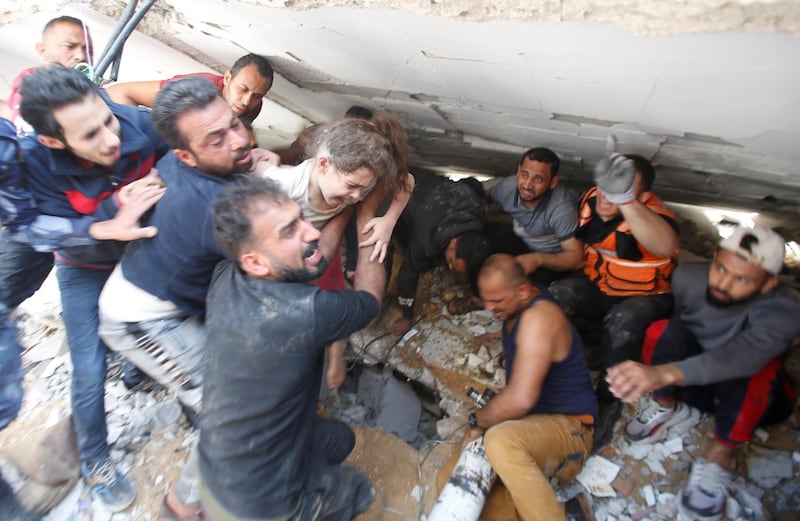 Rescuers carry a girl as they search for victims amid rubble at the site of Israeli air strikes, in Gaza City May 16, 2021. REUTERS/Mohammed Salem