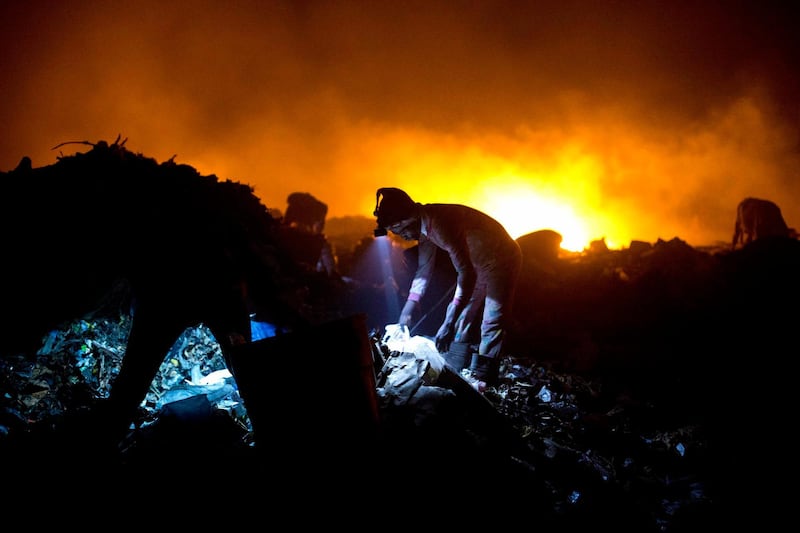 Trash scavengers work with headlamps as they look for useful items. AP Photo