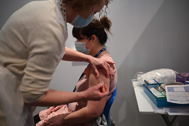 A vaccinator administers an injection of AstraZeneca/Oxford Covid-19 vaccine to a patient at the vaccination centre set up at Chester Racecourse, in Chester, northwest England, on February 15, 2021.  Prime Minister Boris Johnson on February 14 called Britain hitting a target of inoculating 15 million of the most vulnerable people with a first coronavirus jab "a significant milestone", as the country prepared for the next phase of its vaccination programme. / AFP / Oli SCARFF
