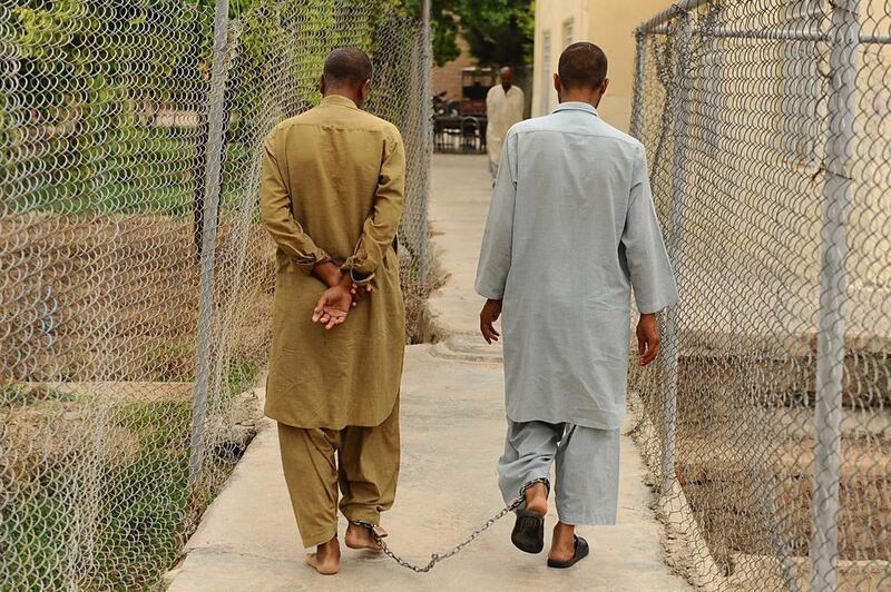 Patients who have been chained together for security purposes walk along a fenced pathway in the centre.