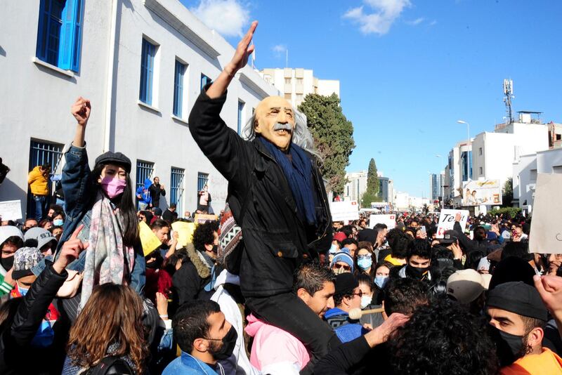 Demonstrators, one wearing a carnival mask, demonstrate in Tunis. AP