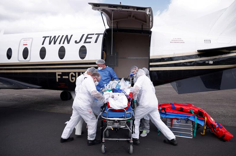 Medical staff carry a patient suffering from Coid-19 on a stretcher after arriving on a plane at Vannes airport. Reuters