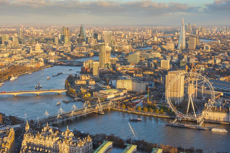 Aerial view across the River Thames and the Southbank, also showing the London Eye and surrounding Lambeth all bathed in warm sunlight.