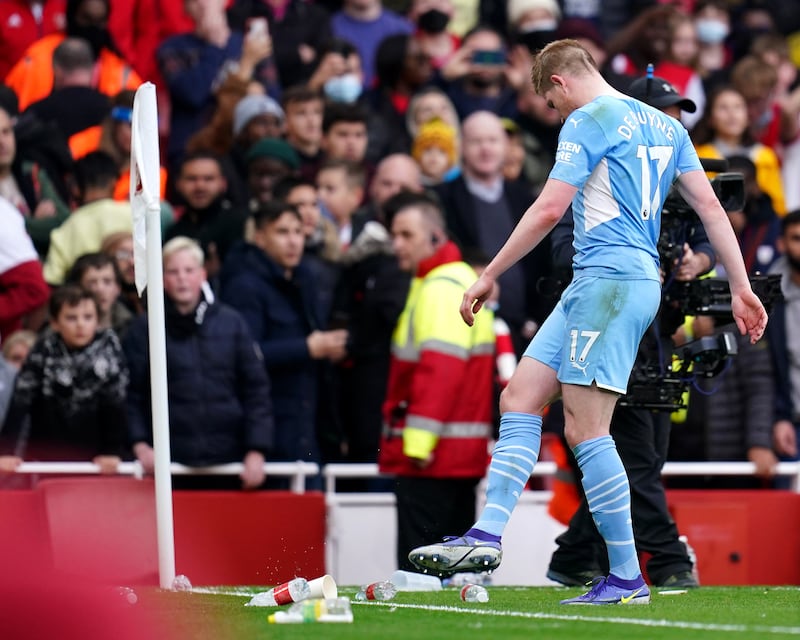 Manchester City's Kevin De Bruyne kicks away bottles and rubbish that was thrown onto the pitch after they scored a second goal against Arsenal at the Emirates Stadium on Saturday,  January 1, 2022. PA