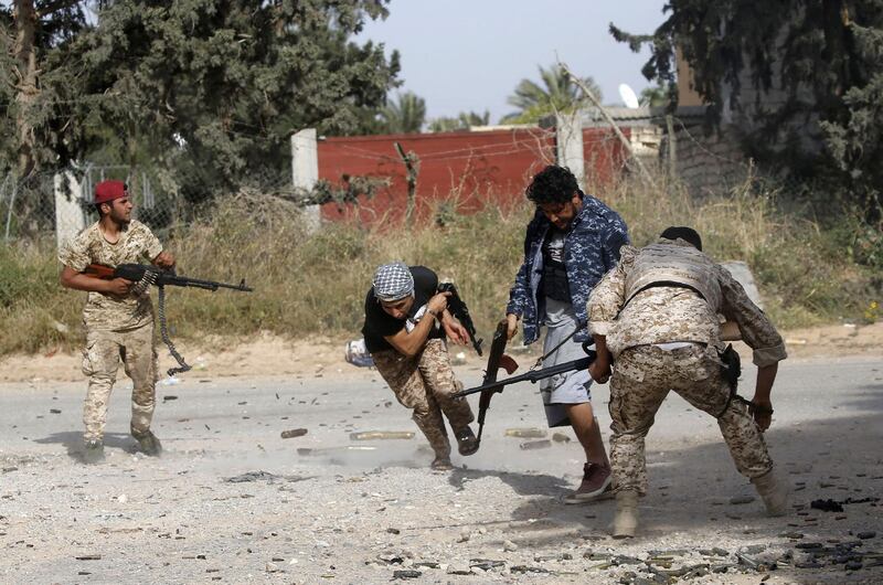 TOPSHOT - Libyan fighters loyal to the Government of National Accord (GNA) run as they fire their guns during clashes with forces loyal to strongman Khalifa Haftar south of the capital Tripoli's suburb of Ain Zara, on April 20, 2019.  Forces loyal to Libya's unity government announced today a counter-attack against military strongman Khalifa Haftar's fighters, as clashes south of the capital Tripoli intensified. / AFP / Mahmud TURKIA
