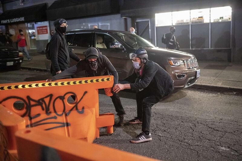 Black bloc protesters pull a barrier into the street while running from police in Portland, Oregon. AFP