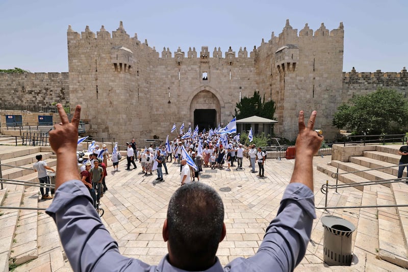 A Palestinian protester flashes the victory sign at Israelis lifting national flags at Damascus Gate in Jerusalem. AFP