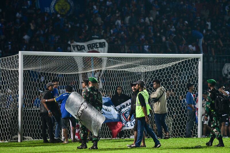 Indonesian army and police attempt to secure the pitch after a football match between Arema FC and Persebaya Surabaya at Kanjuruhan stadium in Malang, East Java. At least 129 people died at the stadium when fans invaded the pitch and police responded with tear gas, triggering a stampede, officials said. AFP