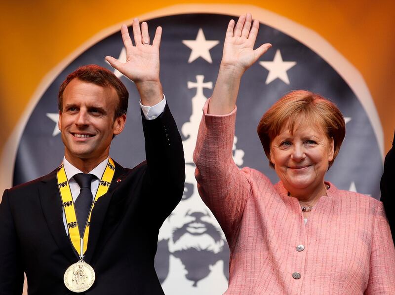 epa06725179 French President Emmanuel Macron (L) and German Chancellor Angela Merkel (R) greet on stage after the Charlemagne Prize (Karlspreis) ceremony at the town hall in Aachen, Germany, 10 May 2018. The International Charlemagne Prize of the German City of Aachen is awarded annually since 1950 to people who have contributed to the ideals upon which Europe has been founded.  EPA/RONALD WITTEK