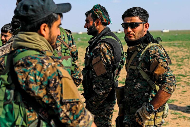 Fighters with the US-backed Syrian Democratic Forces (SDF) gather at a scanning area for people who are evacuated from the Islamic State (IS) group's embattled holdout of Baghouz,
during an operation to expel IS jihadists from the area, in the eastern Syrian province of Deir Ezzor, on February 25, 2019.   US-backed forces evacuated over 40 truckloads of people from the Islamic State group's last Syria redoubt today, as they sought to clear out civilians before a final push to crush the jihadists. / AFP / Delil souleiman
