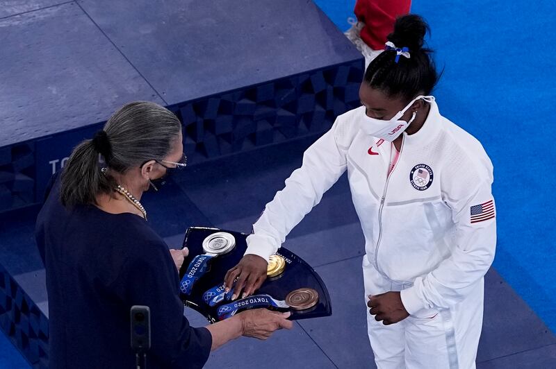 Simone Biles, of the United States, picks up her bronze medal after the women's artistic gymnastics balance beam final.