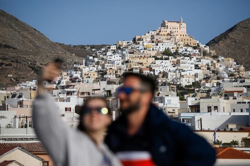 People pose for a selfie on the upper deck of a ferry from the port of Piraeus in Athens to the Island of Mykonos, Greece, stopping here at Siros Island on October 4, 2020. (Photo by David GANNON / AFP)
