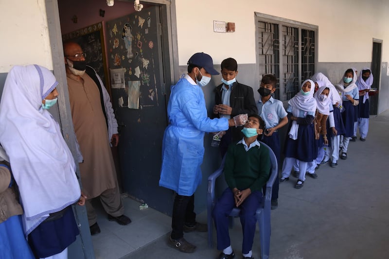 A health worker tests school pupils for Covid-19 during a surge in cases of Omicron in Karachi, Pakistan. The country has recorded more than 4,000 coronavirus cases for the second consecutive day. EPA